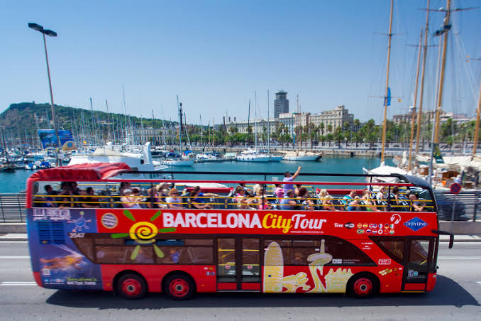 Otevřený vyhlídkový autobus v Barceloně u přístavu — noční trasa míjí nasvícený Port Vell